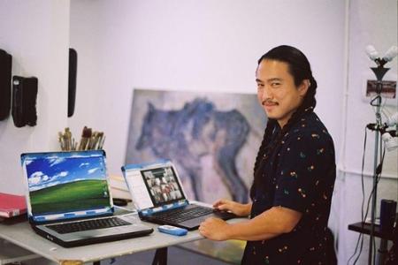 画室里的艺术家站在两台彩绘笔记本电脑前